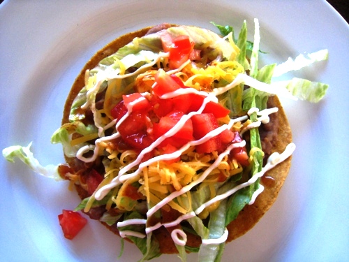 Bean Tostada on a plate with sour cream drizzle