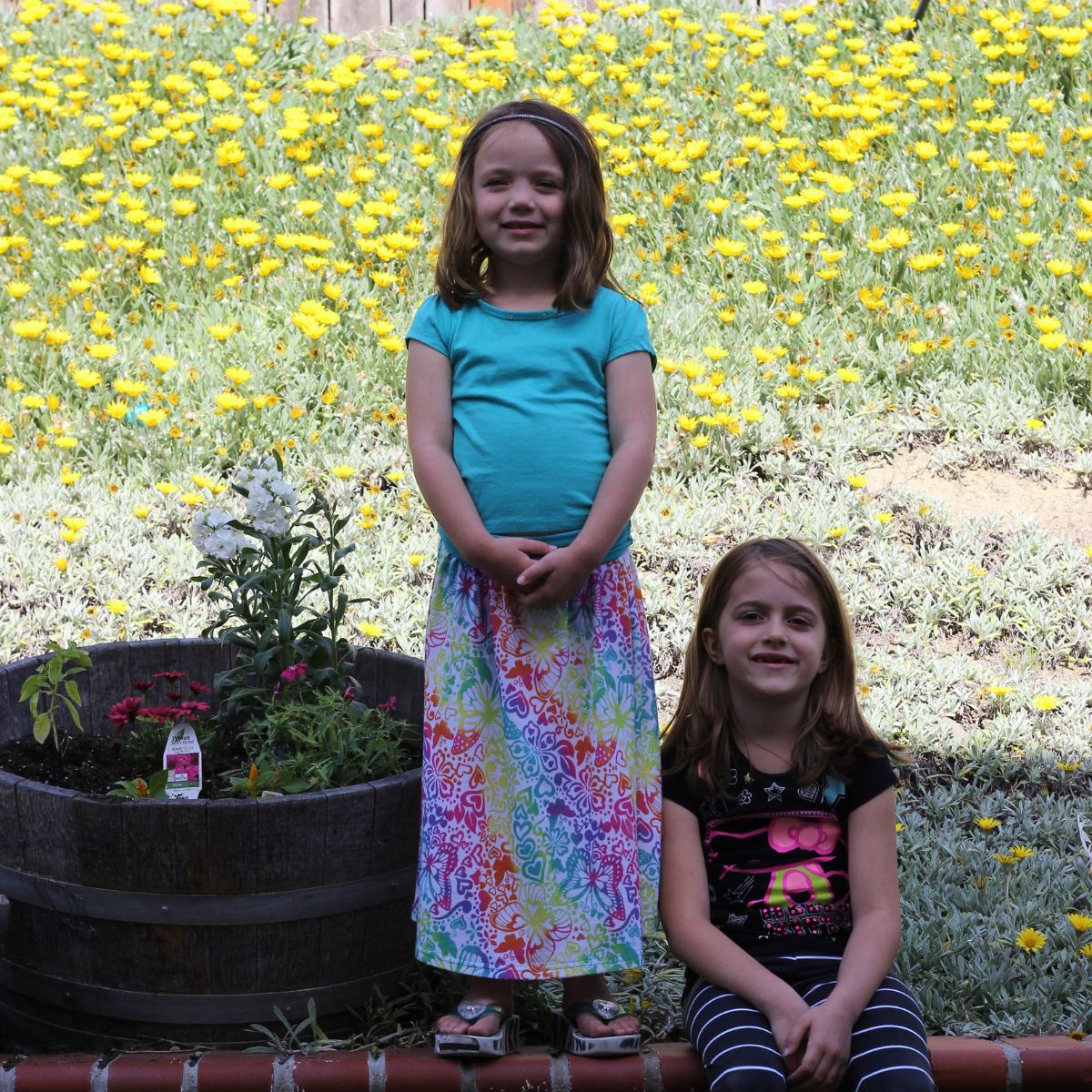 girls near a flower planter with newly planted flowers with tags.