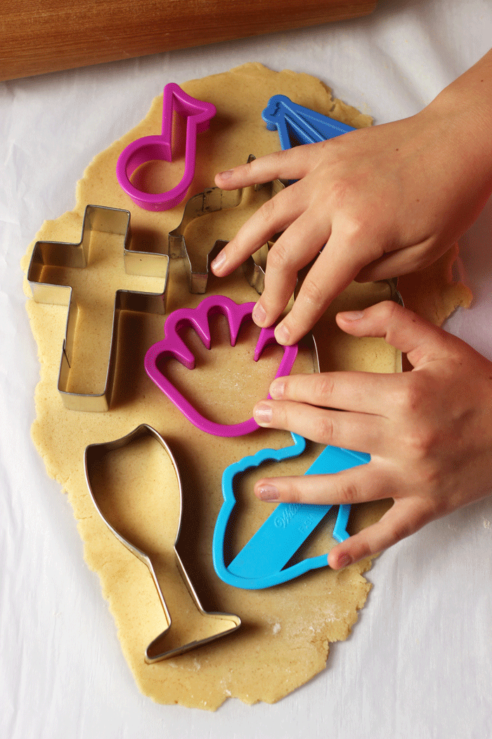 child's hand cutting cookies out of dough