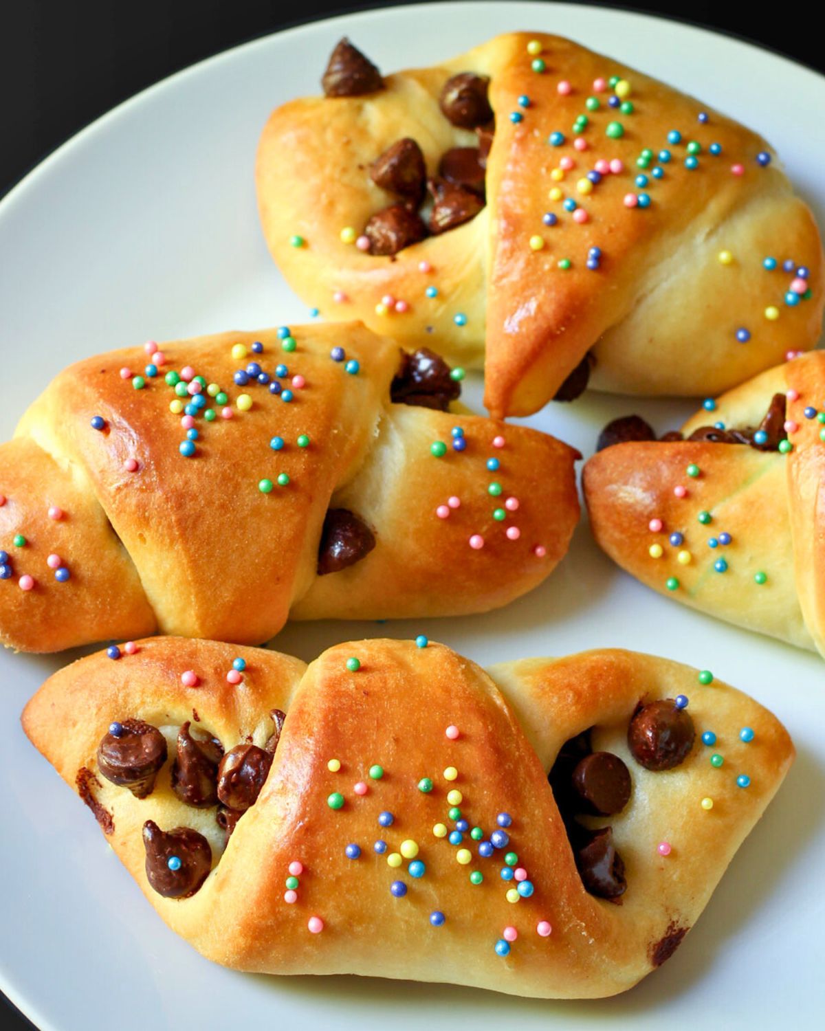 white plate of chocolate butterhorn rolls with colored sprinkles.