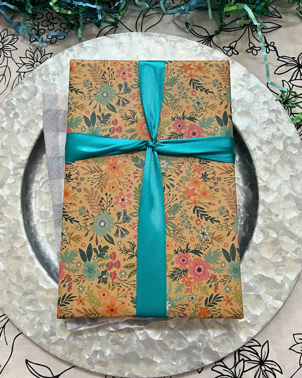 floral wrapped gift on dinner place setting.