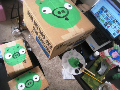 Cardboard boxes turned into green pigs for Angry Birds game.