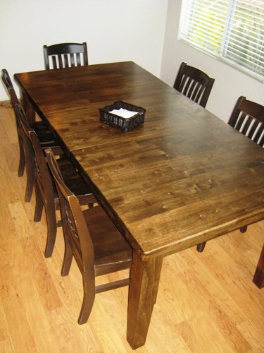 A wood dining room table with a stack of napkins.