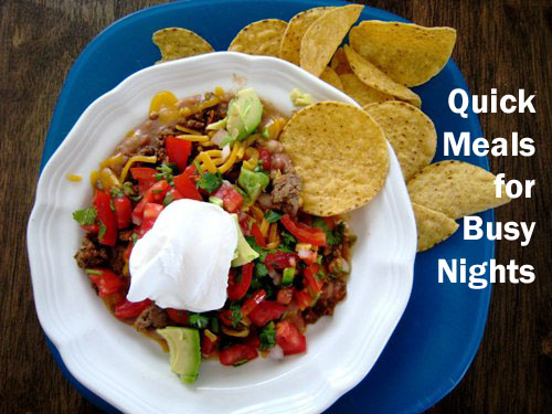 A bowl of nacho toppings on plate of chips