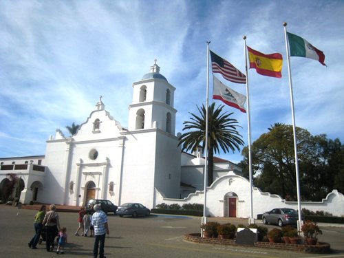 A group of people walking in front of Mission San Luis Rey de Francia.