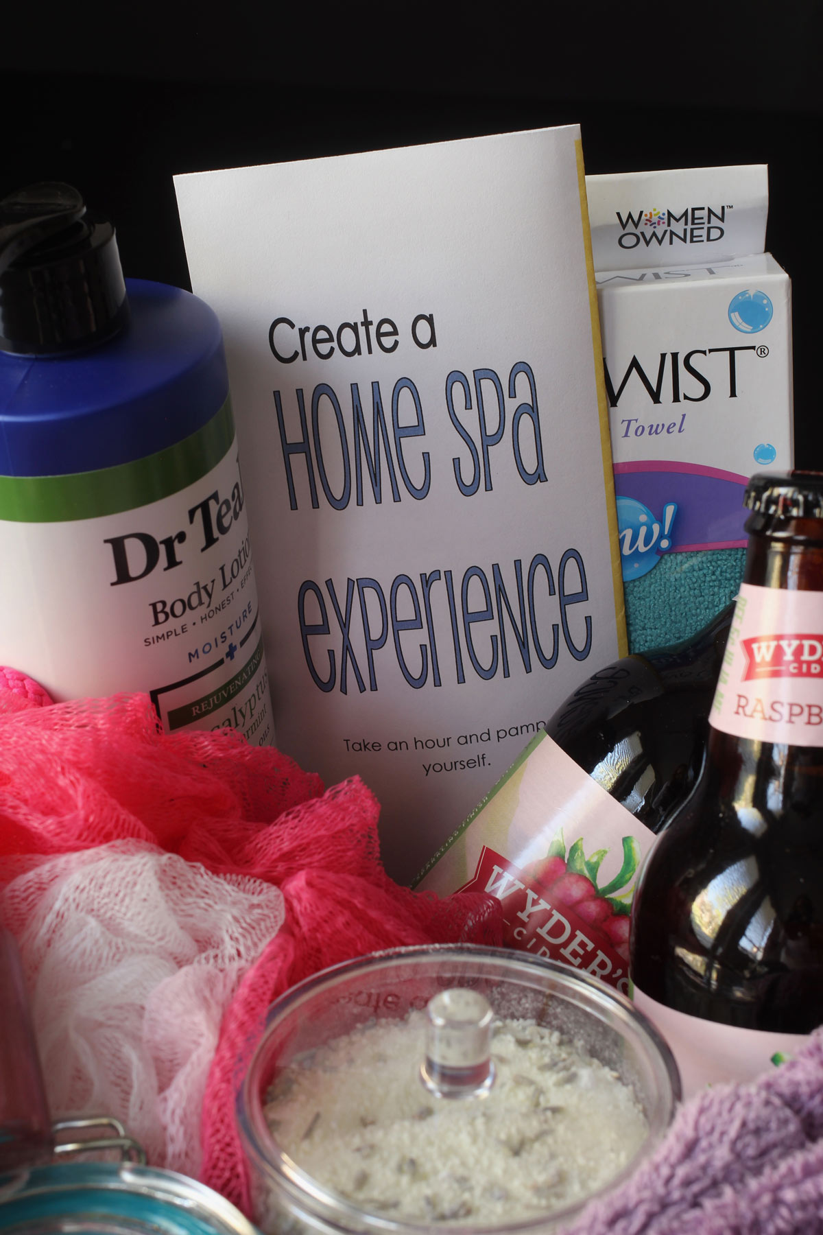 close up of filled spa gift basket in front of a black background.