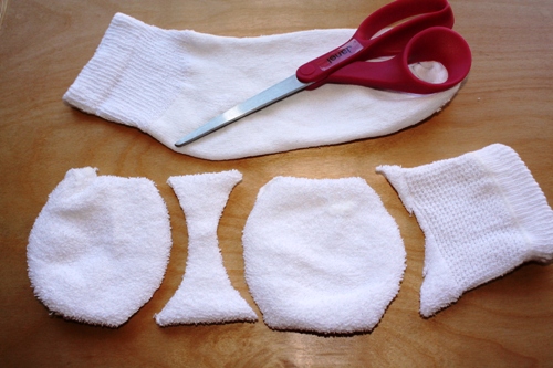 Cutting a sock into snowball shapes with red scissors.