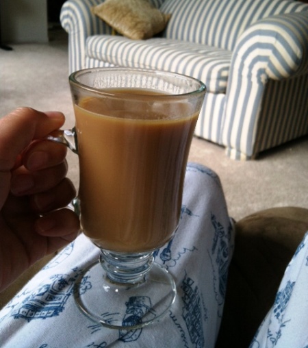 holding mug of coffee on knee in living room.