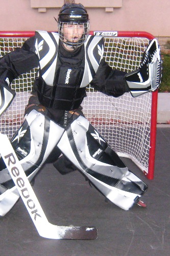 boy playing goalie standing in the hockey goal.