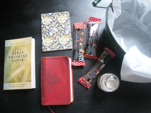 Kind bars, journal, Bible promise book, and candle on table next to basket.