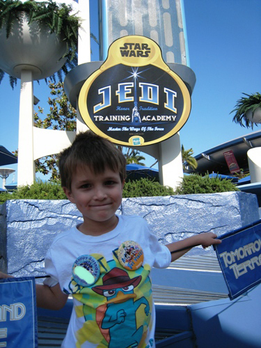 A boy at Disneyland in front of Jedi Training Academy sign.