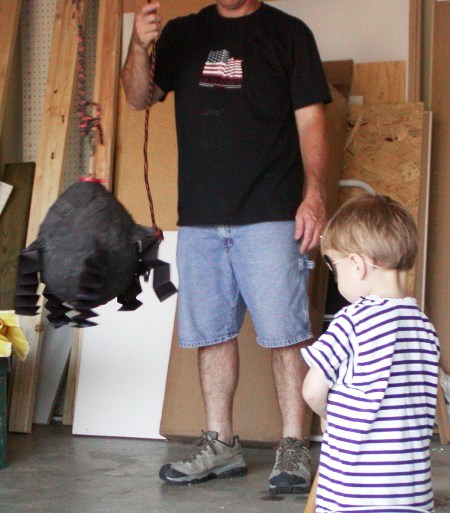 A small boy ready to strike at an Icredibles pinata.