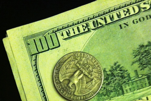 A quarter atop a 100 dollar bill.