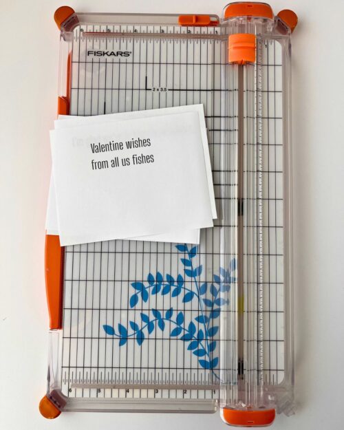 paper cutter and printed cards on white surface.