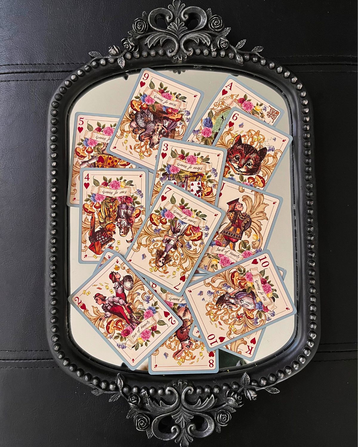 Heart playing cards laid out on a mirrored tray.