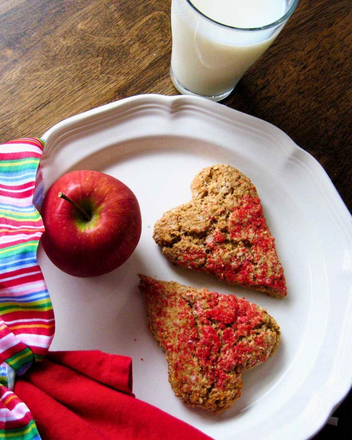 heart-shaped scones on a plate with an apple and a glass of milk.