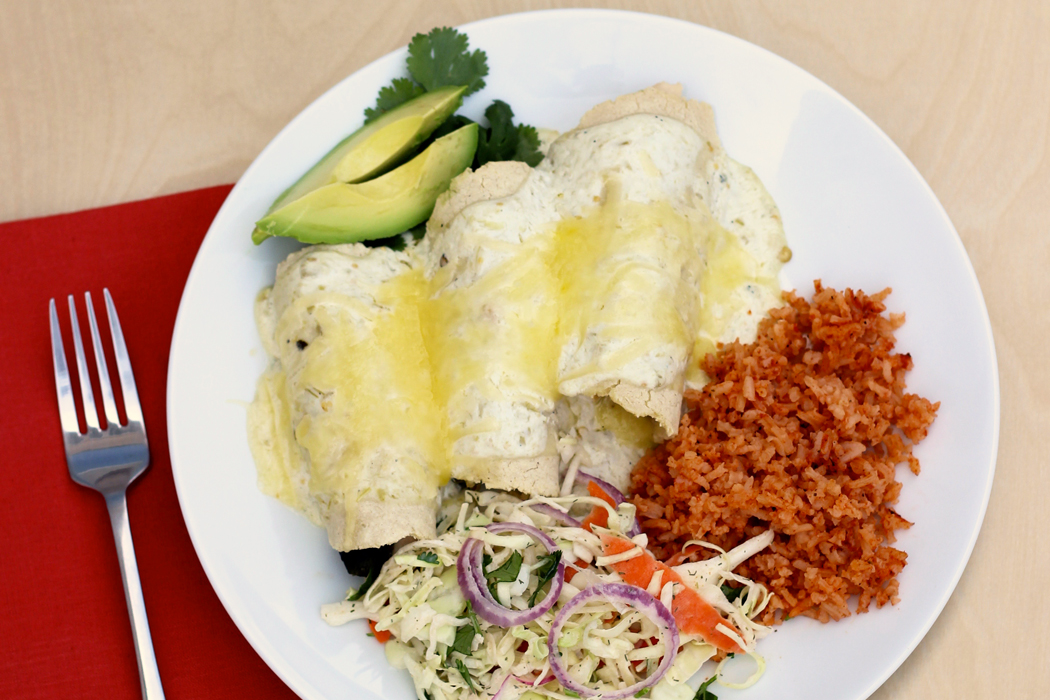 A plate of poblano enchiladas with rice and slaw