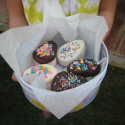 Chocolate-dipped marshmallow eggs in a tin lined with parchment paper.