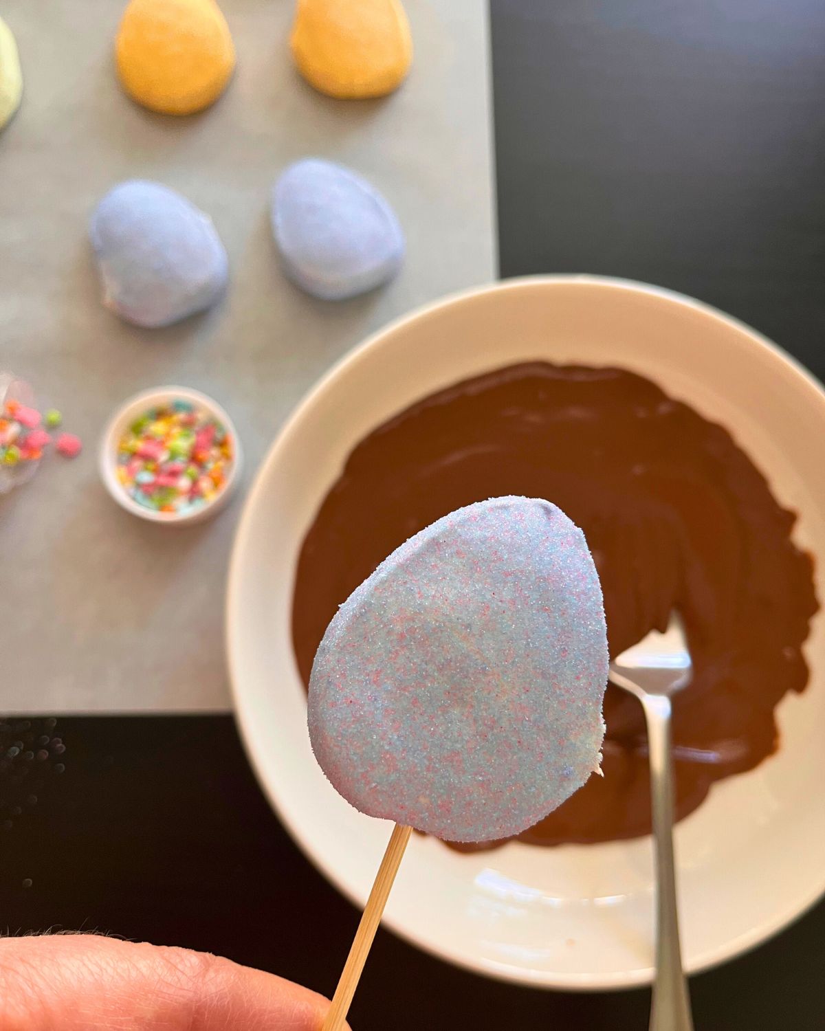 skewered marshmallow held above melted chocolate.