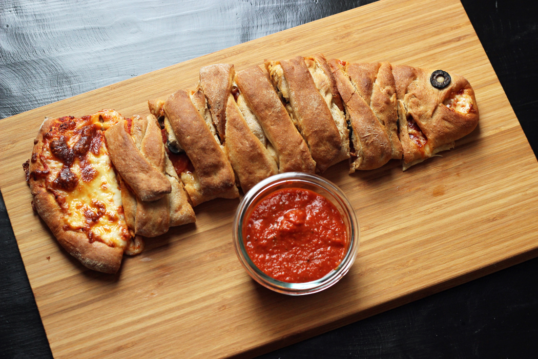 A fish-shaped calzone sliced on top of a wooden cutting board