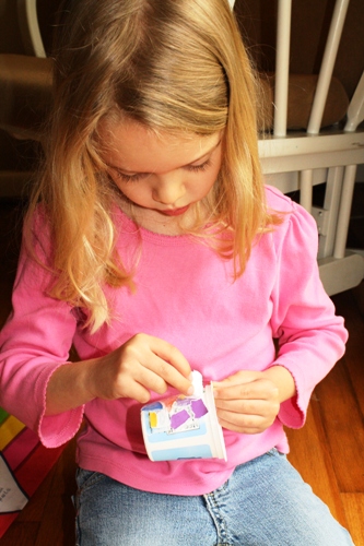 A little girl putting stickers on a vase.