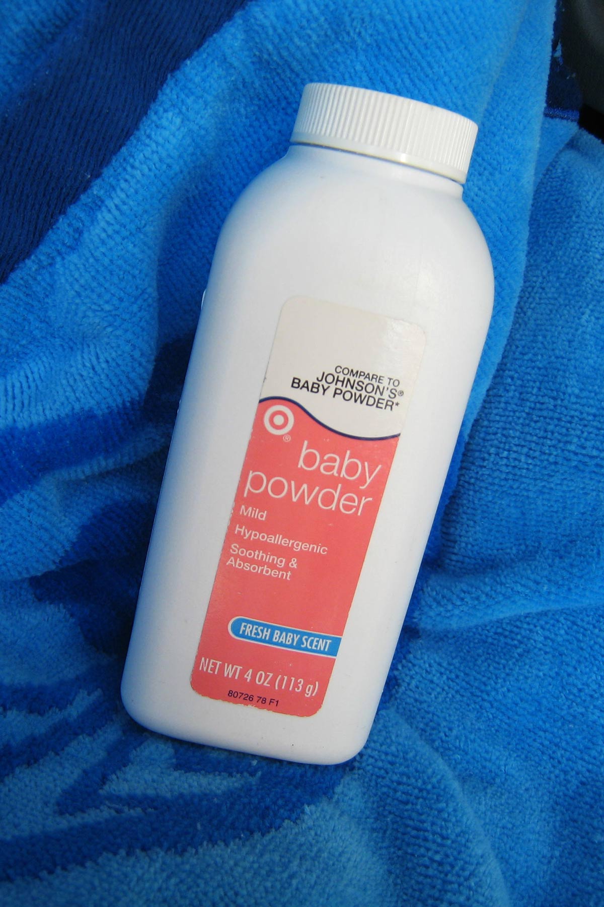 bottle of baby powder on a blue beach towel.