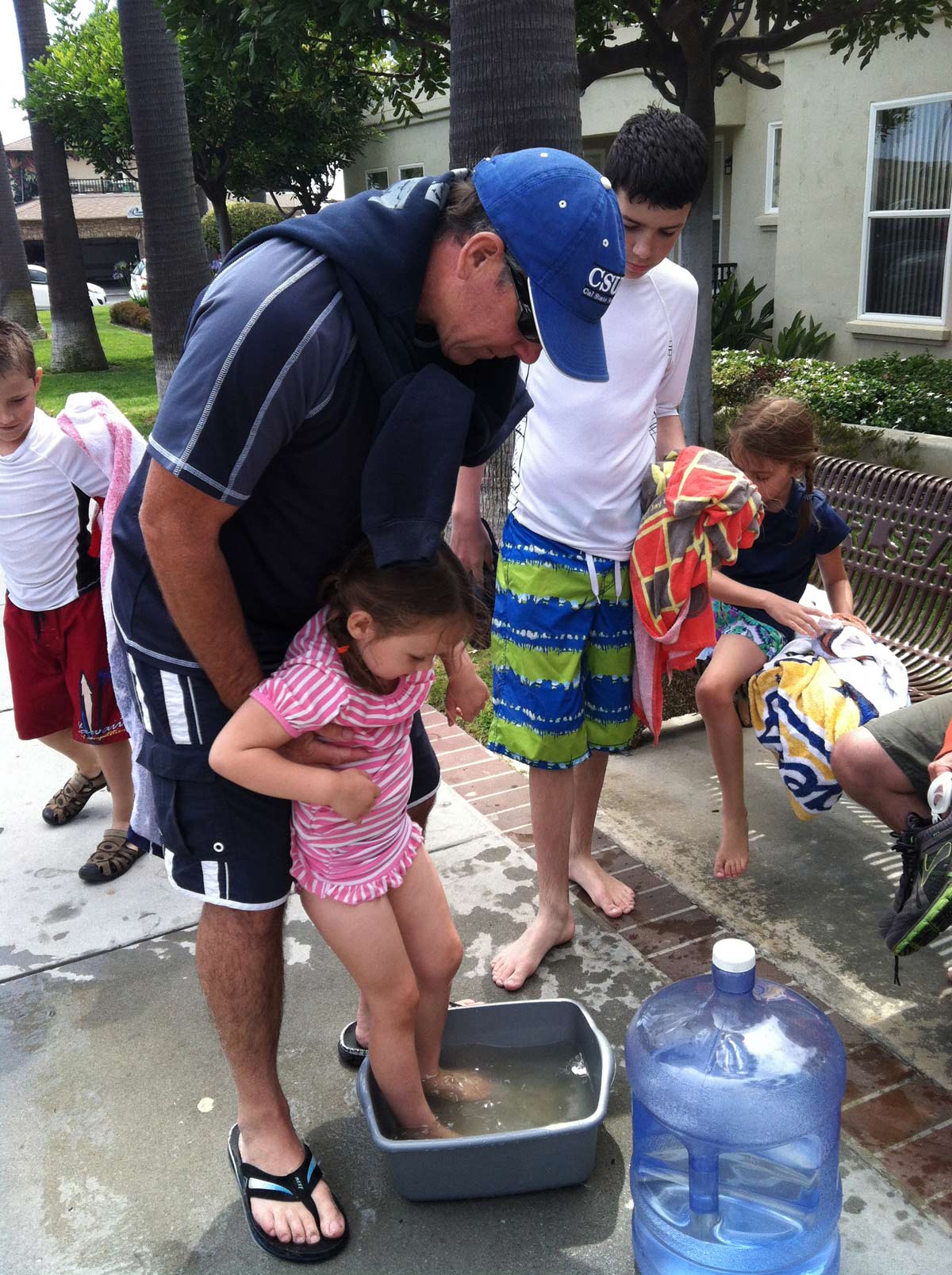 dad and daughter cleaning feet in water basin.