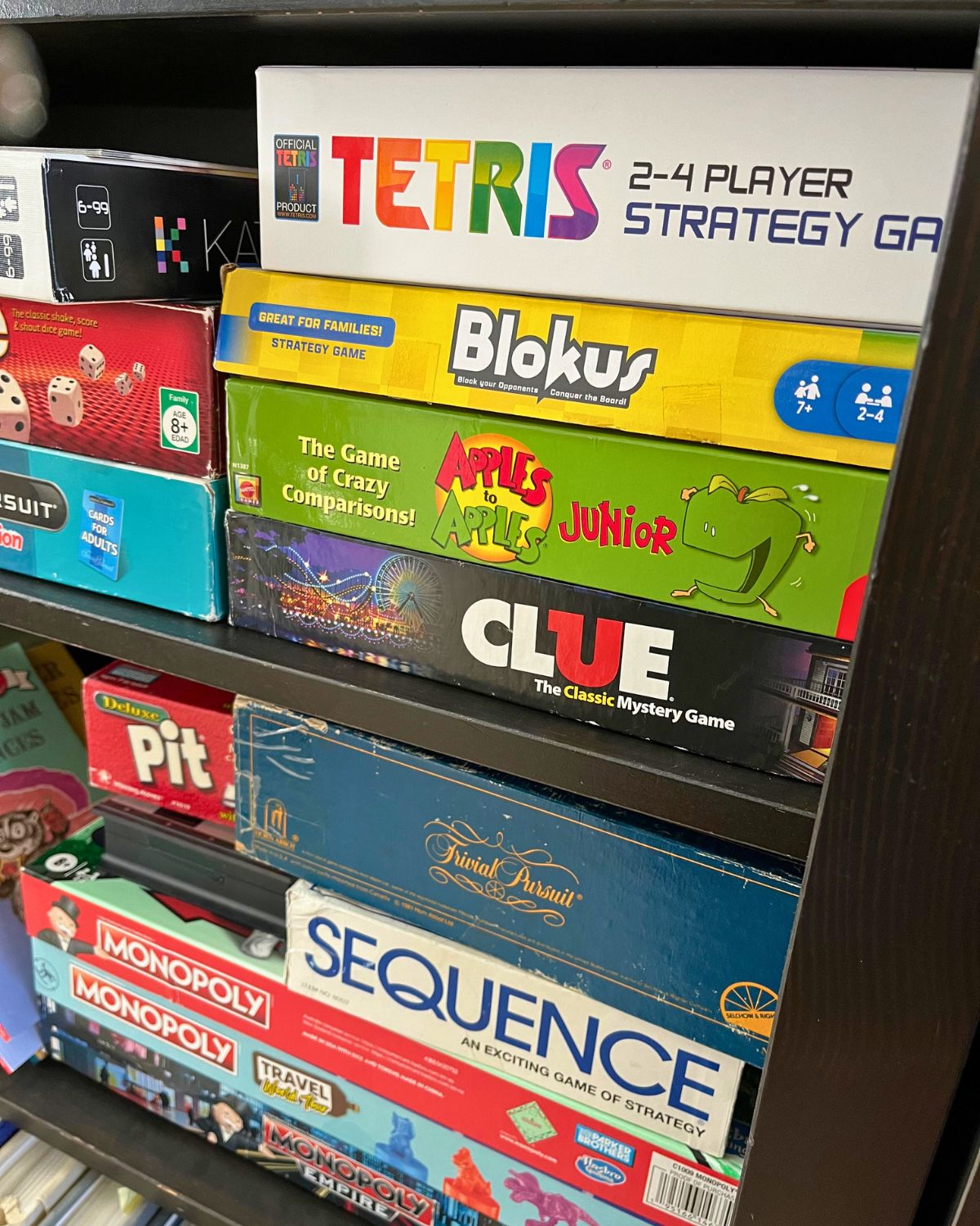 stack of board games on black shelf.