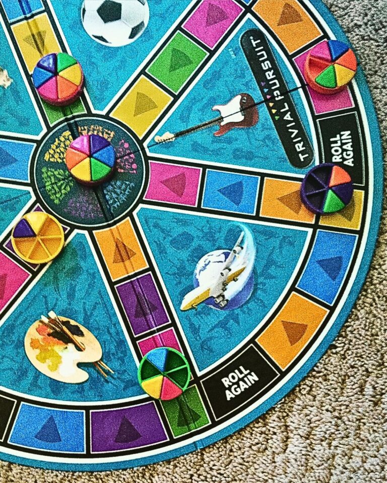 overhead shot of trivial pursuit family with pieces in play.