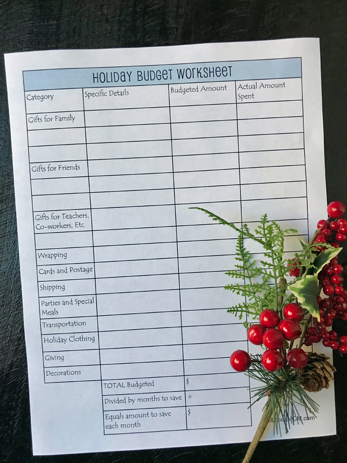 flatlay of holiday budget worksheet with sprig of holly and berries.