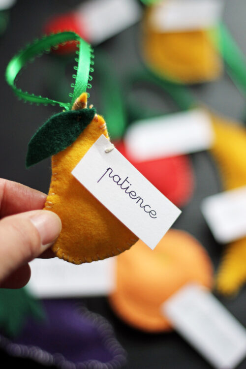 A close up of a fruit felt Christmas ornament with at tag labeled Patience.