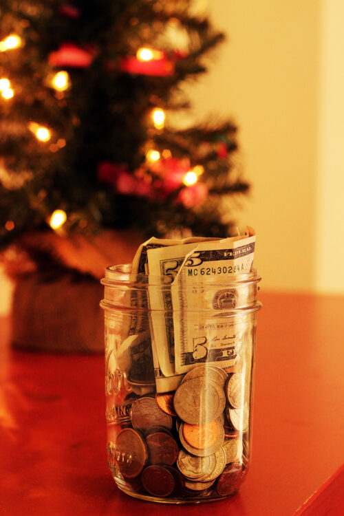 jar of money savings in front of small lit christmas tree