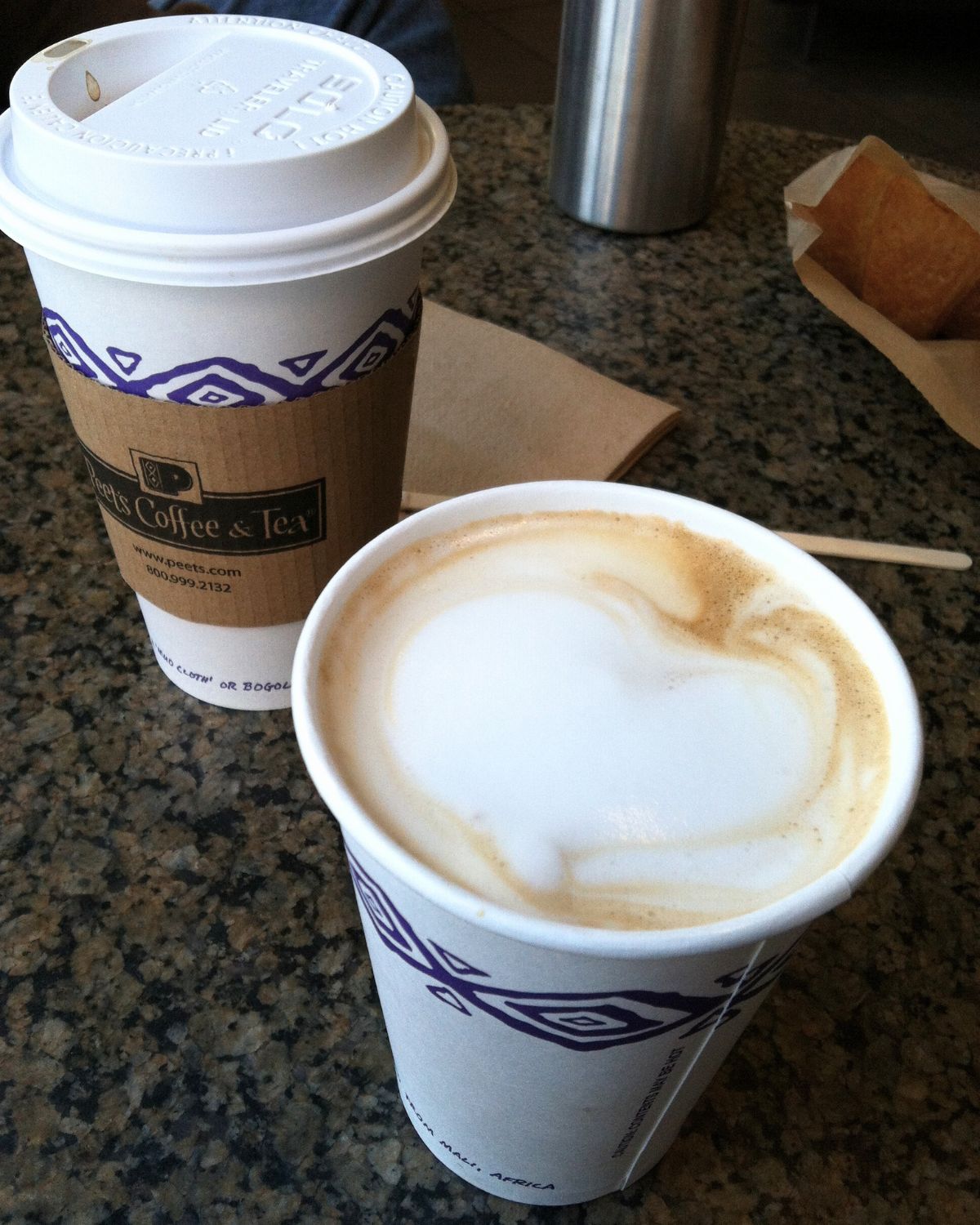 two coffee cups from Peets, one with a heart shaped in the foam.