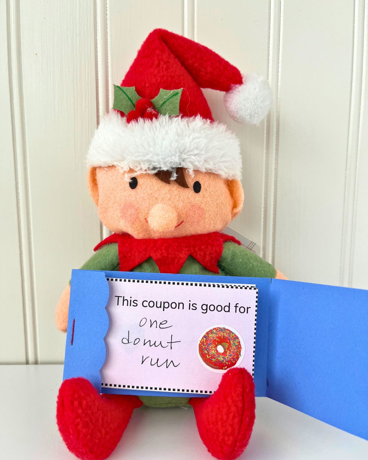 toy elf holding an open coupon book, with the front coupon good for one donut run.