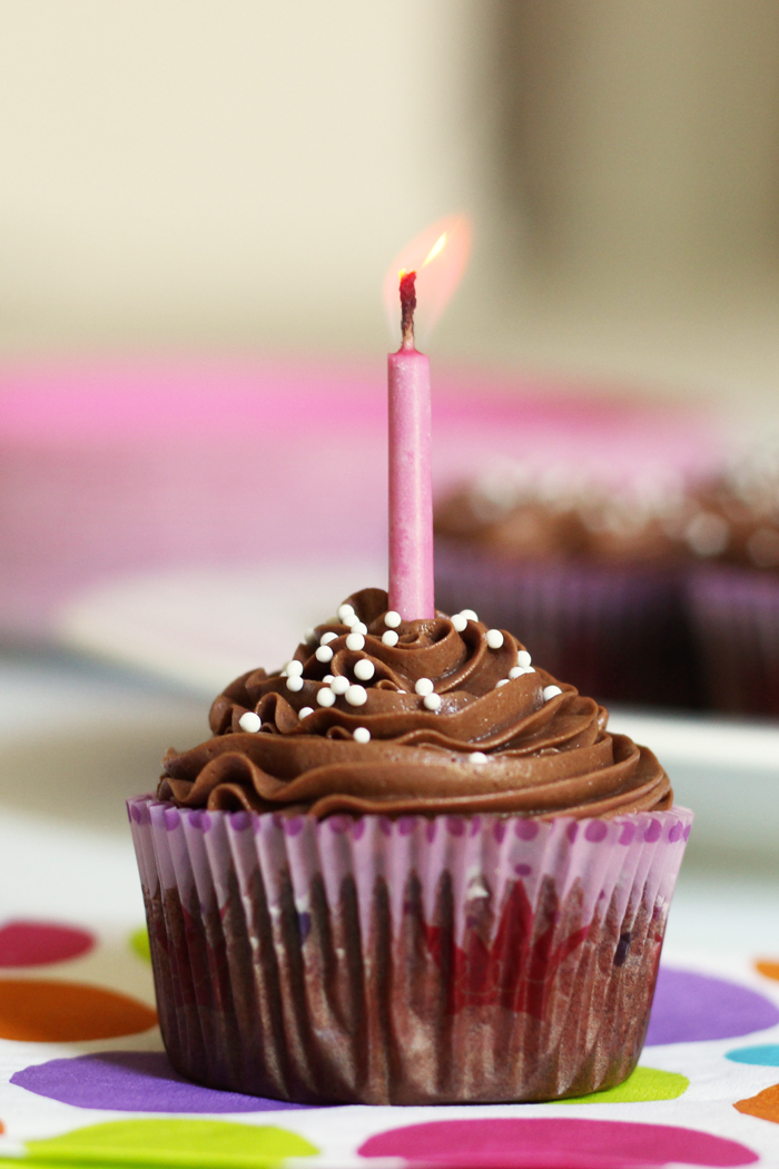 A close up of a cupcake with Chocolate Buttercream and a candle