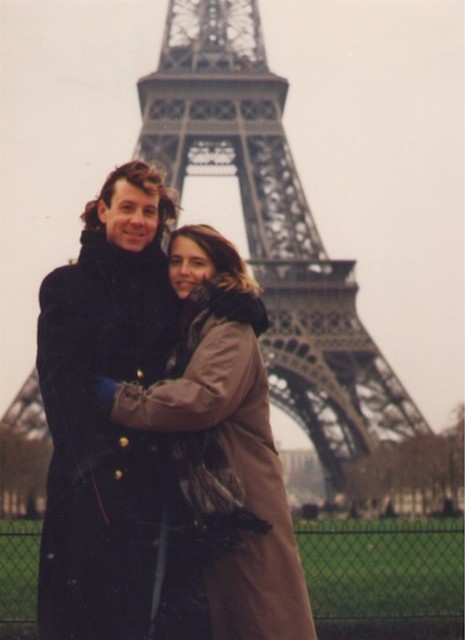 A man and a woman standing in front of the Eiffel tower.