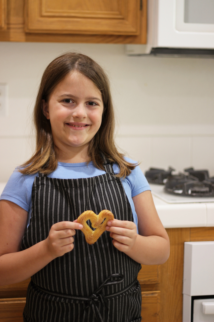 A girl standing in the kitchen with heart cookie