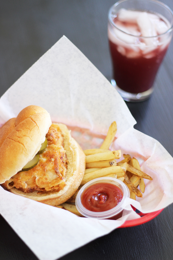 A fried chicken sandwich in a basket with fries and ketchup