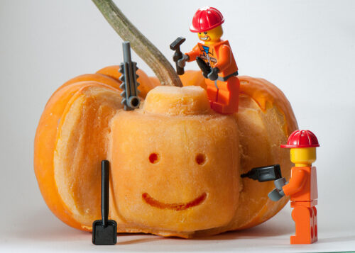 Lego carving a lego head into a pumpkin.