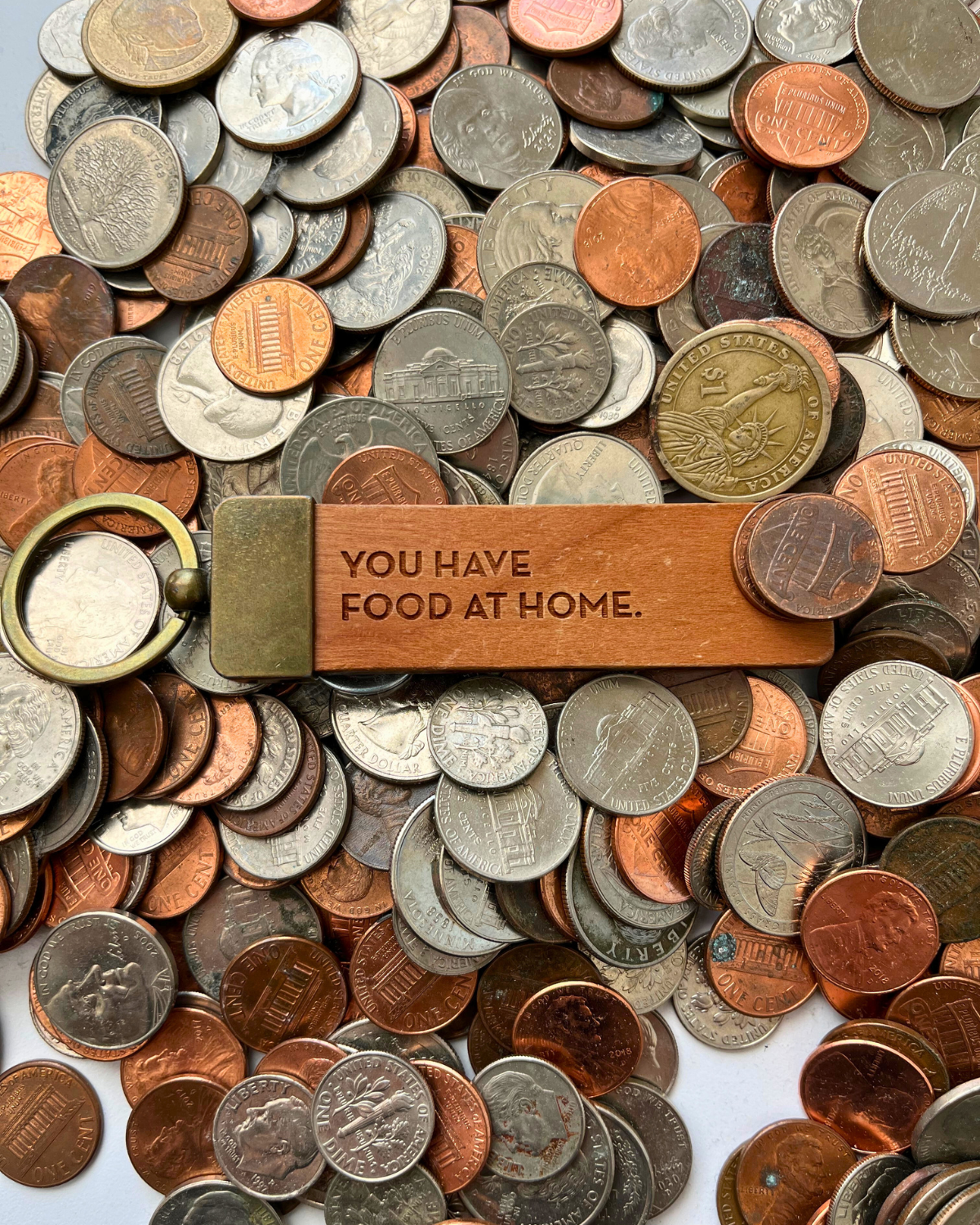keychain with words, "you have food at home" in a pile of coins.