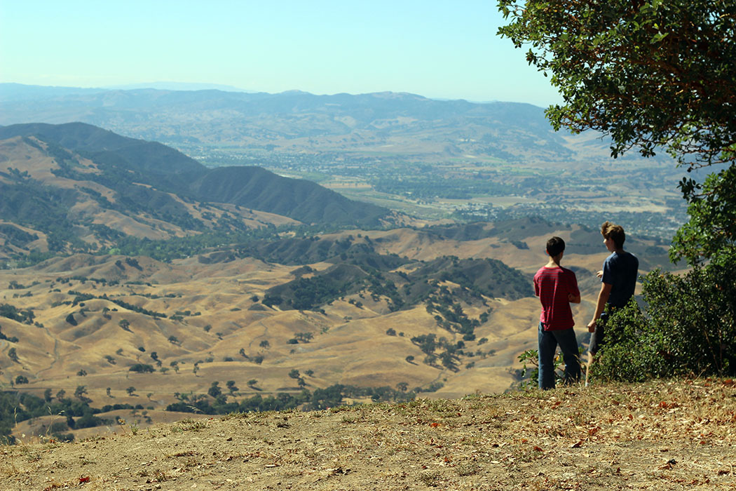 Boys standing in a field with mountain sin the background.