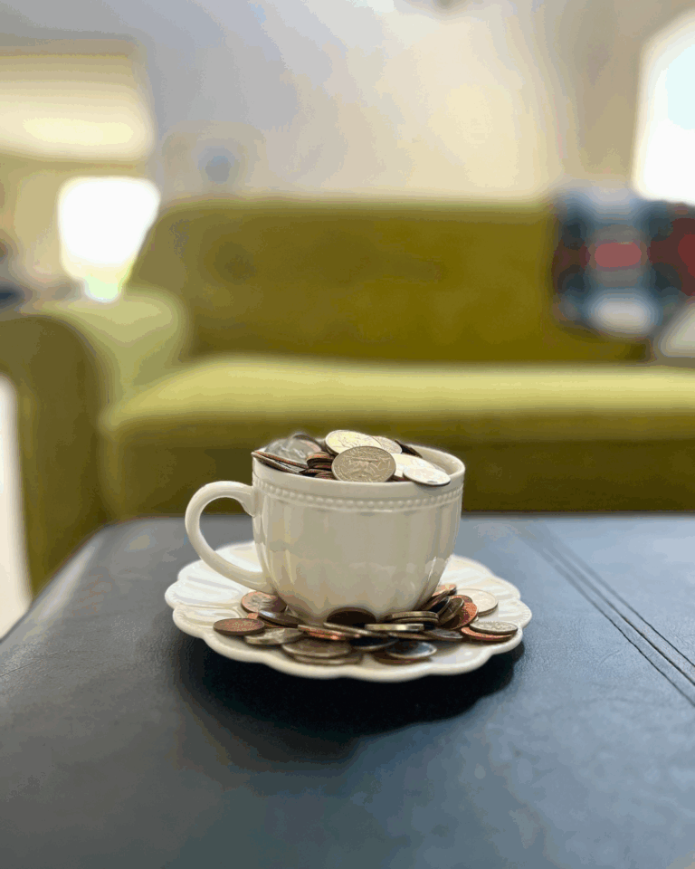 tea cup overflowing with coins to represent the savings of debt-free living.