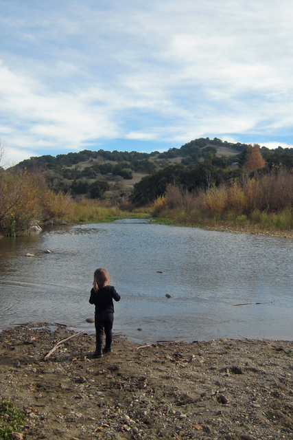 A girl standing next to a body of water.