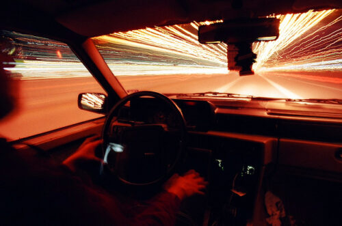 The view through a car window with lights racing along the sides.