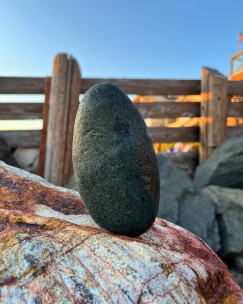 a rock balances on another rock at the beach.