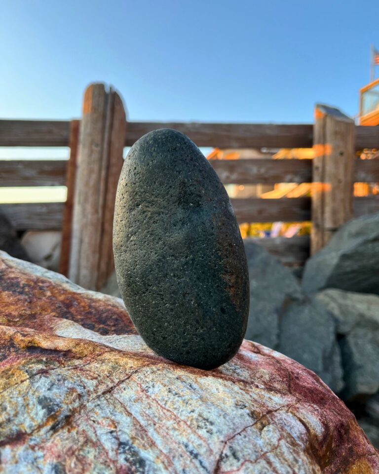 a rock balances on another rock at the beach.