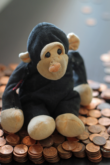 A teddy bear sitting on a table in a pile of pennies.