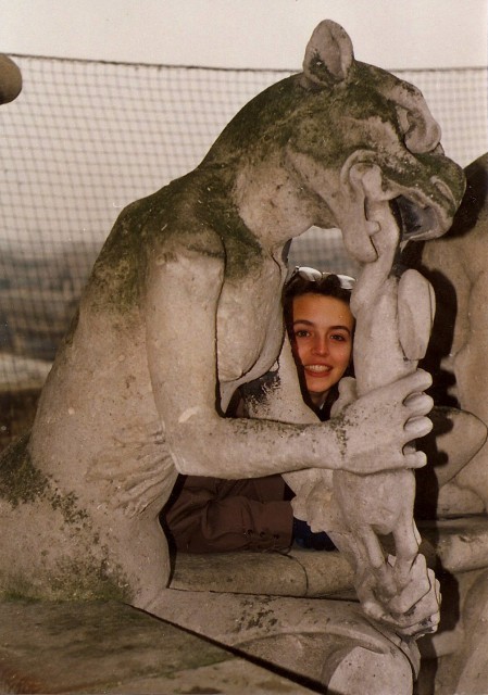 Jessica looking through the opening of a gargoyle's arms on the top of Notre Dame.