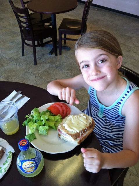 A girl sitting at a table with a plate of food.