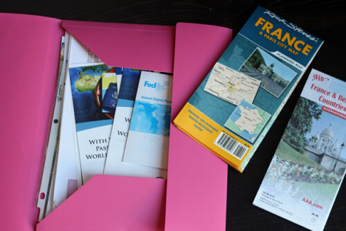 A pink folder with maps and travel information on a table.